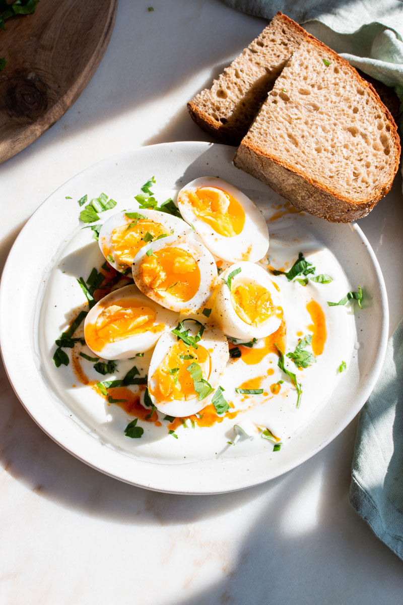 Joghurt-Kräuter-Eier mit Bauernbrot auf Teller angerichtet