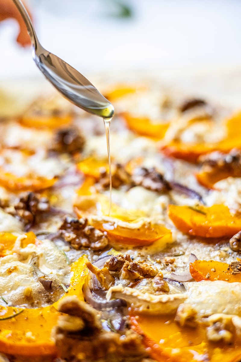 Honig wird auf fertigen Flammkuchen geträufelt