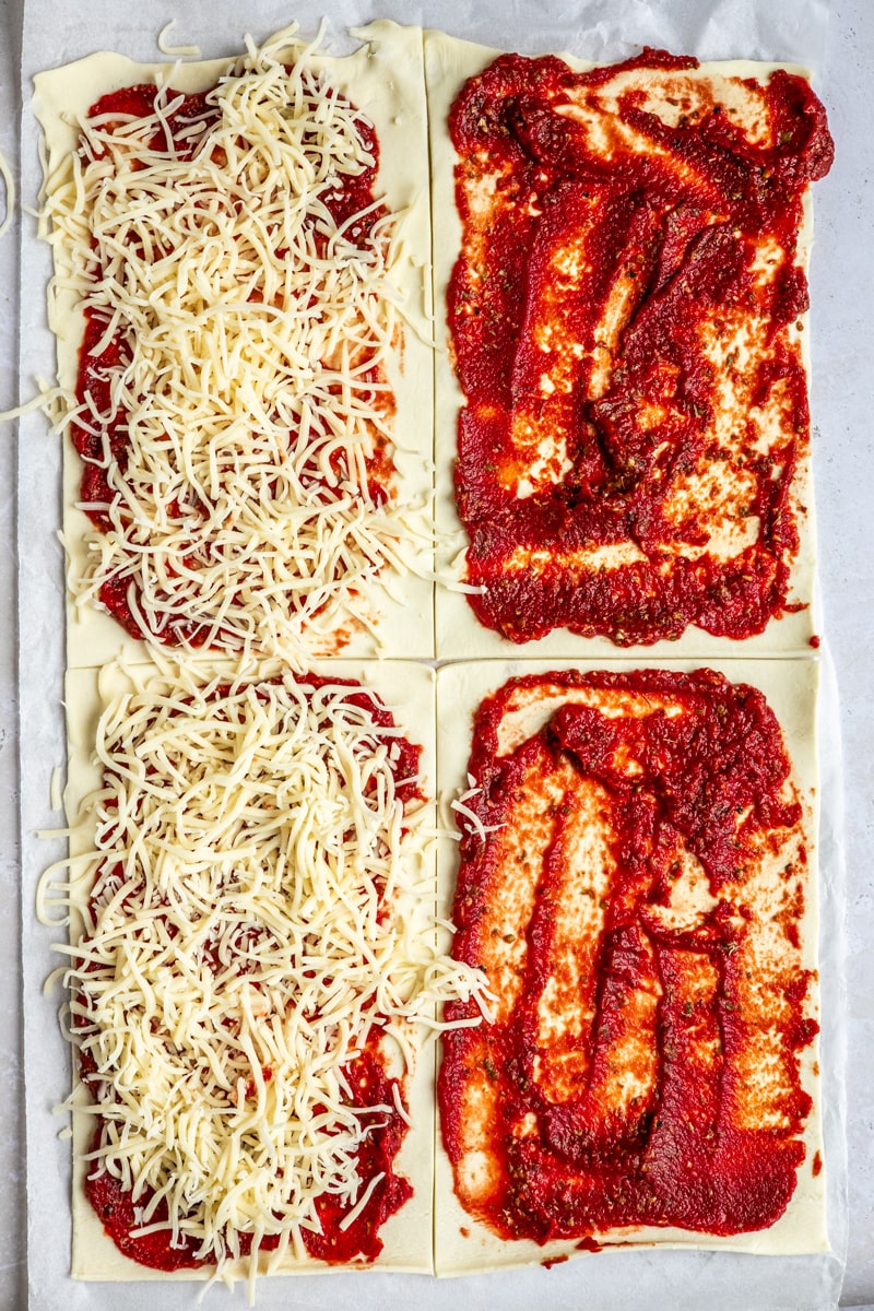 Blätterteig mit Tomatenmark bestrichen und mit Käse belegt