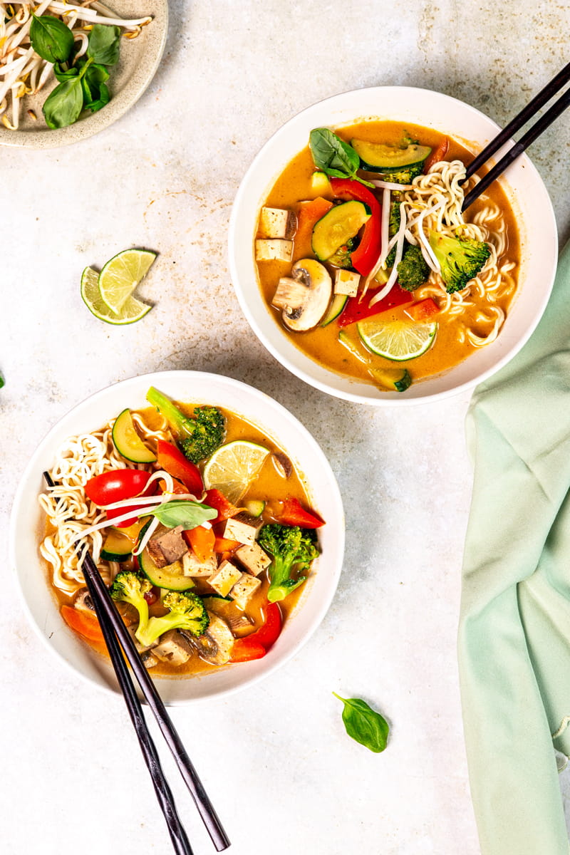 Thai-Kokos-Suppe mit Stäbchen in zwei Tellern