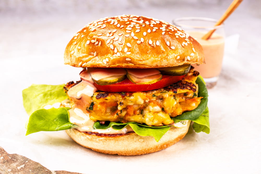 Halloumi-Burger mit Burgersauce im Hintergrund